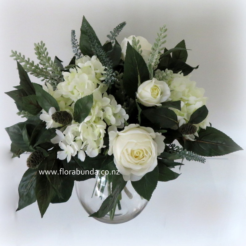 glass vase of dark green and white flowers fake
