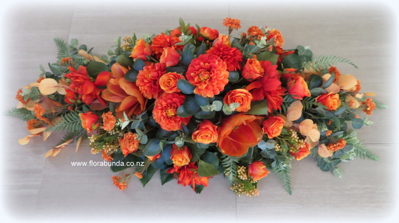 Orange funeral flowers for Coffin top